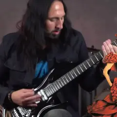 Mężczyzna gra na gitarze, a obok niego tańczy kobieta w czerwonej sukni. To jakby muzyka z "la isla bonita" ożyła.