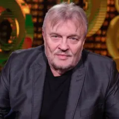 Krzysztof Cugowski, w szarym garniturze, z siwą brodą i włosami, wygląda jakby opowiadał o swoich najlepszych utworach.
