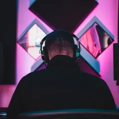 DJ w słuchawkach tworzy taneczne hity wszechczasów w studiu z neonowym oświetleniem.