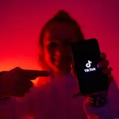 Osoba w czerwonym świetle pokazuje telefon z logo TikToka. To idealne miejsce na krótkie, zabawne filmiki, które przyciągają uwagę jak tantiemy.