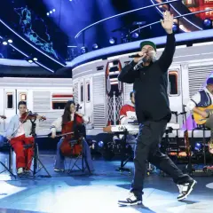 Wokalista na scenie podczas festiwalu Opole, z orkiestrą smyczkową i gitarzystą w tle.