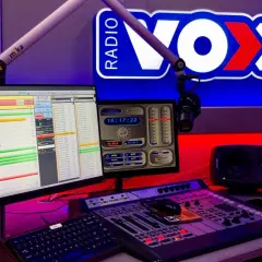 Studio radiowe VOX FM z mikrofonem, konsolą mikserską i monitorami.