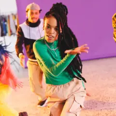 Grupa młodych ludzi tańczy w rytm muzyki dancehall. Energetyczne ruchy i kolorowe stroje tworzą radosną atmosferę.