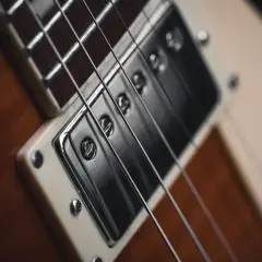 Zbliżenie na przetwornik i struny gitary elektrycznej. Może to być okładka do **bunkr album** z rockową muzyką.
