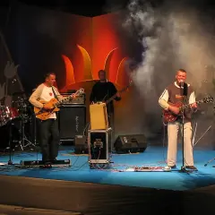 Zespół gra na scenie. Wokalista śpiewa, gitarzyści grają. Raz, dwa, trzy utwory i publiczność szaleje.