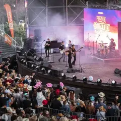 Na scenie podczas Piknik Country Mrągowo gra zespół, a publiczność w kapeluszach bawi się w rytm muzyki.