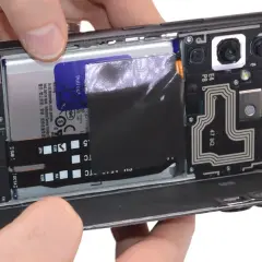 Rozkręcony telefon z widoczną baterią i modułem aparatu. Dowiedz się, jak włączyć mikrofon w telefonie, sprawdzając jego wewnętrzne komponenty.