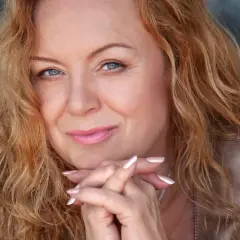 Hanna Banaszak z rudymi włosami i niebieskimi oczami, wpatrzona w obiektyw, jakby opowiadała historie zawarte w swoich utworach.