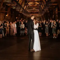 Para młoda tańczy pierwszy taniec przy blasku świateł. Goście obserwują wzruszający moment, idealny do wyboru piosenki na pierwszy taniec.