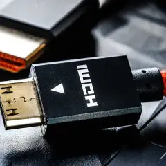 Złote wtyczki HDMI, jeden z nich z czerwonym, plecionym kablem, gotowe do podłączenia.