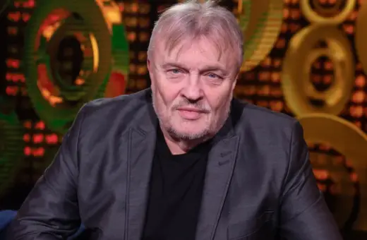 Krzysztof Cugowski, w szarym garniturze, z siwą brodą i włosami, wygląda jakby opowiadał o swoich najlepszych utworach.