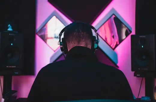 DJ w słuchawkach tworzy taneczne hity wszechczasów w studiu z neonowym oświetleniem.