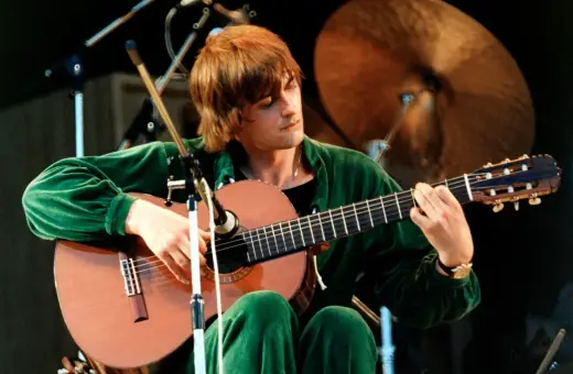 Mężczyzna w zielonym dresie gra na gitarze, a jego twarz skrywa się w **moonlight shadow**.