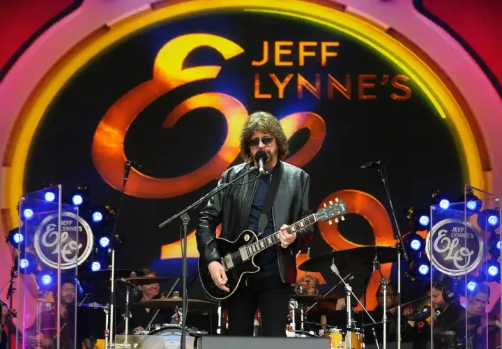 Jeff Lynne z Electric Light Orchestra na scenie, wykonuje swoje kultowe utwory. W tle logo zespołu.