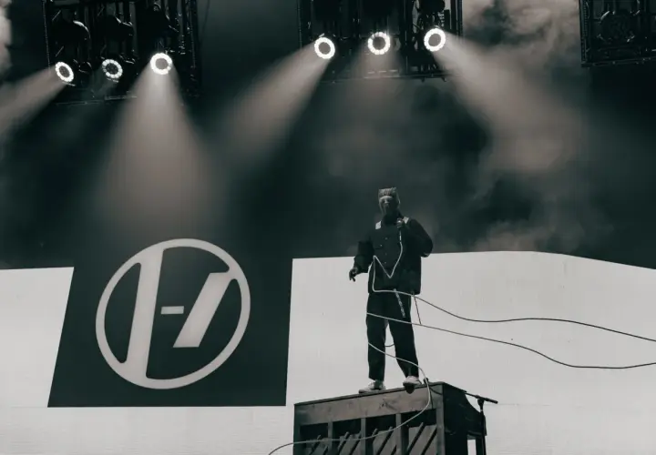 Tyler Joseph z Twenty One Pilots na scenie w Łodzi, w charakterystycznym stroju, na tle logo zespołu.