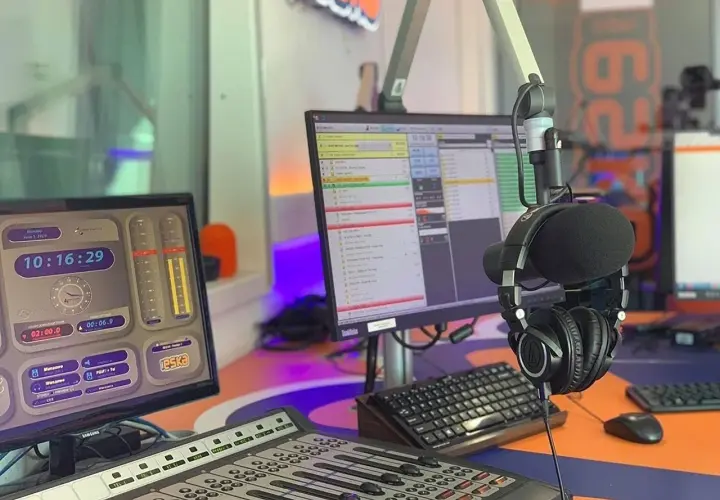 W studiu radiowym, gdzie słychać muzykę z **radio eska2 online**, wiszą słuchawki. Na monitorach widać zegar i program radiowy.