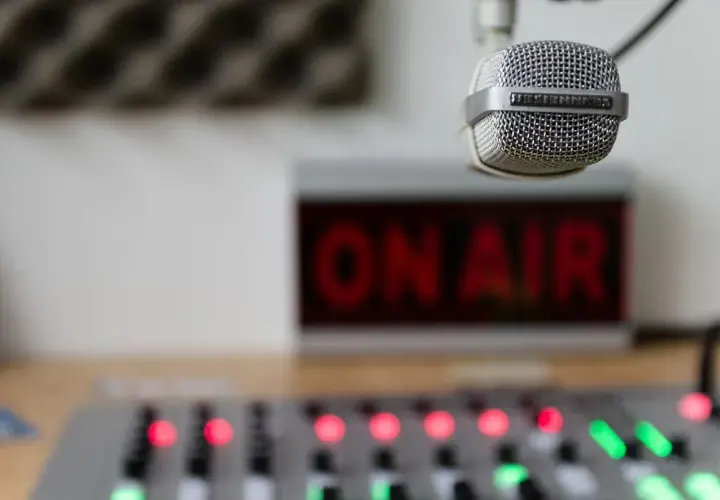 Mikrofon gotowy do nadawania, czerwony napis "ON AIR" i konsoleta. Słychać nas na **eska częstotliwość**!