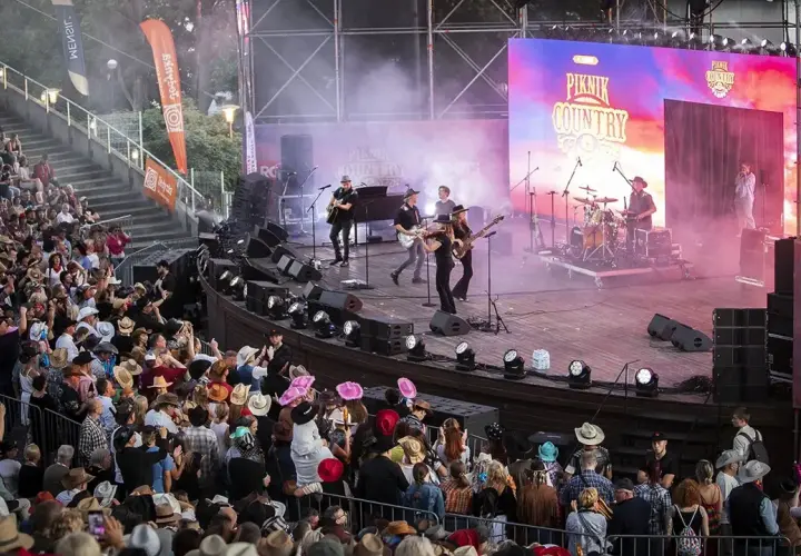 Na scenie podczas Piknik Country Mrągowo gra zespół, a publiczność w kapeluszach bawi się w rytm muzyki.