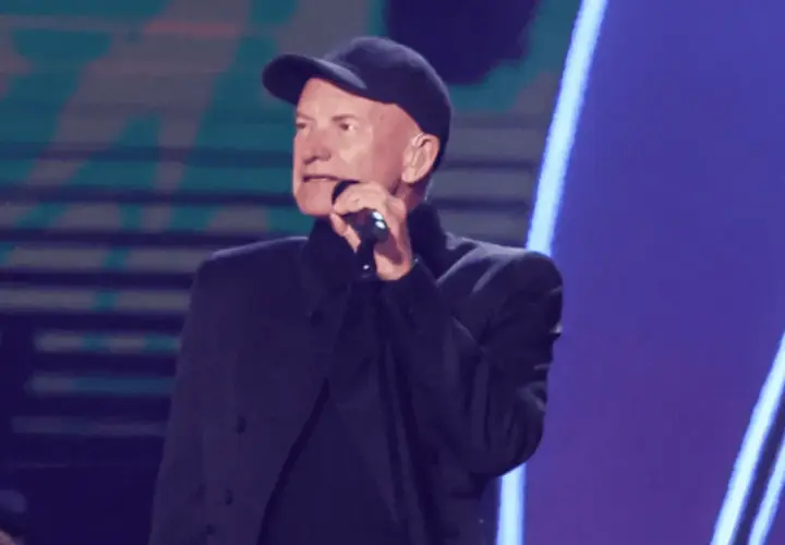 Sting w czapce i czarnym stroju śpiewa do mikrofonu. Ciekawe, ile Sting bierze za koncert, gdy występuje na tak dużej scenie.