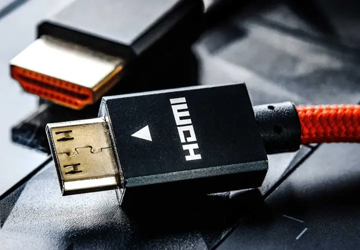 Złote wtyczki HDMI, jeden z nich z czerwonym, plecionym kablem, gotowe do podłączenia.