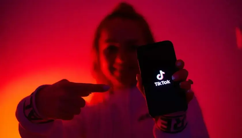 Osoba w czerwonym świetle pokazuje telefon z logo TikToka. To idealne miejsce na krótkie, zabawne filmiki, które przyciągają uwagę jak tantiemy.