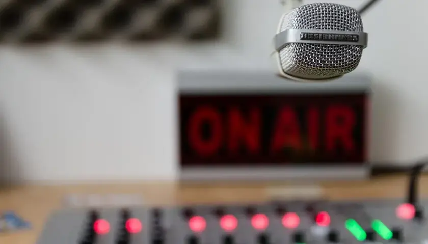 Mikrofon gotowy do nadawania, czerwony napis "ON AIR" i konsoleta. Słychać nas na **eska częstotliwość**!