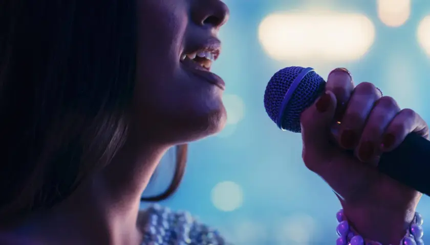 Kobieta śpiewa do mikrofonu, jej głos rozbrzmiewa w rytm muzyki. To idealny moment na playback.