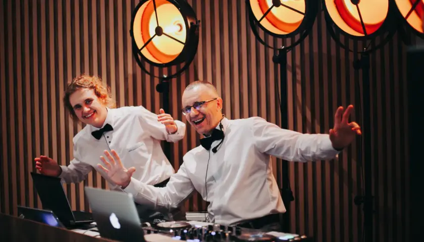 Dwóch DJ-ów w białych koszulach i czarnych muszkach, gotowych do zabawy. Zastanawiasz się, ile kosztuje dj na wesele?