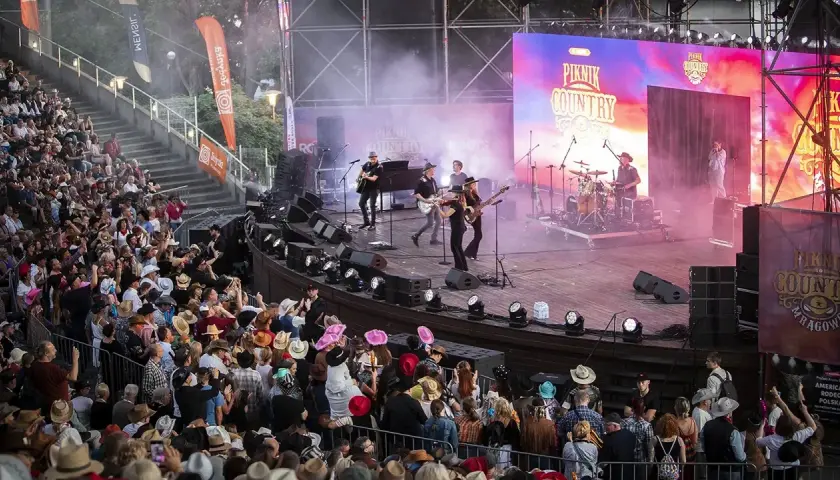 Na scenie podczas Piknik Country Mrągowo gra zespół, a publiczność w kapeluszach bawi się w rytm muzyki.