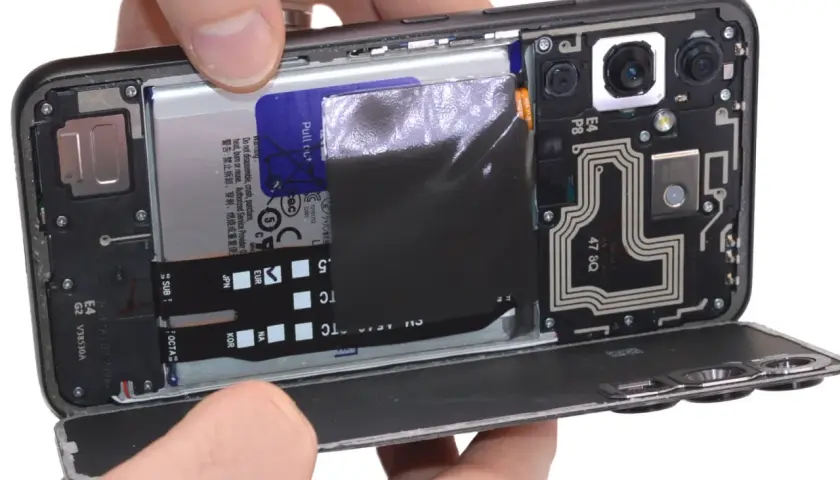 Rozkręcony telefon z widoczną baterią i modułem aparatu. Dowiedz się, jak włączyć mikrofon w telefonie, sprawdzając jego wewnętrzne komponenty.