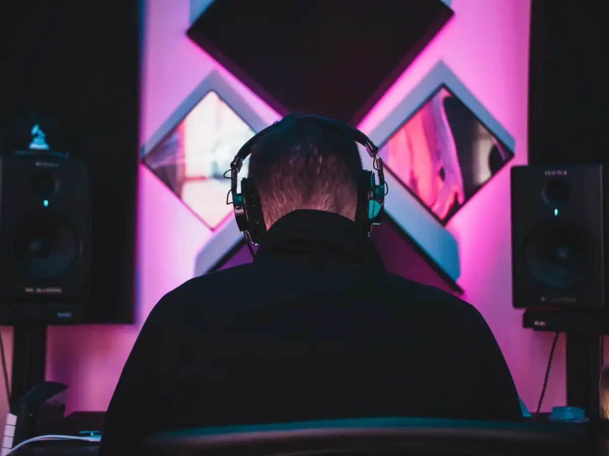 DJ w słuchawkach tworzy taneczne hity wszechczasów w studiu z neonowym oświetleniem.
