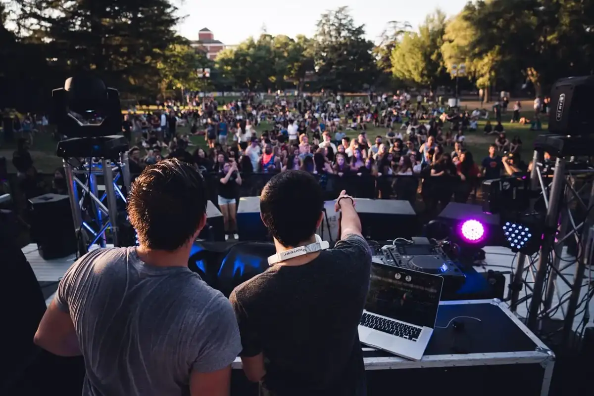 DJ-e tworzą atmosferę deep house na koncercie plenerowym. Tłum bawi się przy muzyce.