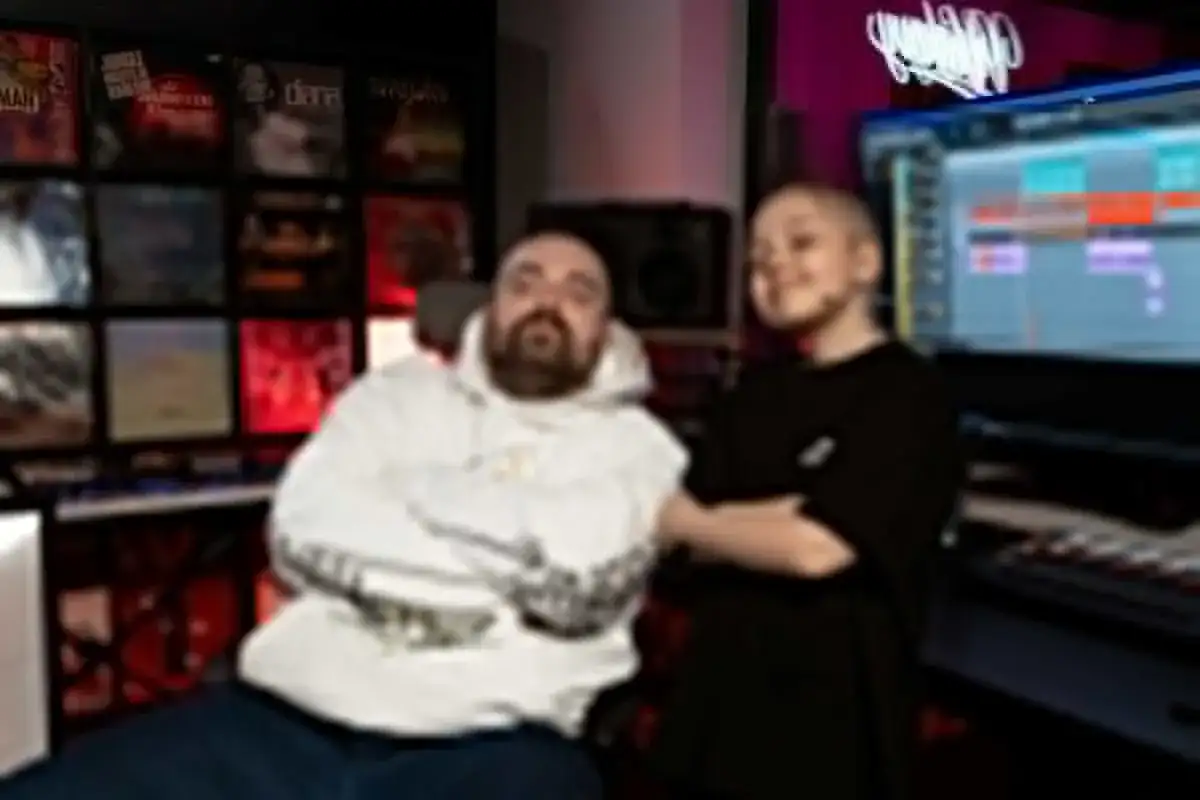 Bedoes i młody raper w studiu, tworzą muzykę. W tle płyty winylowe i ekran komputera z programem do produkcji.