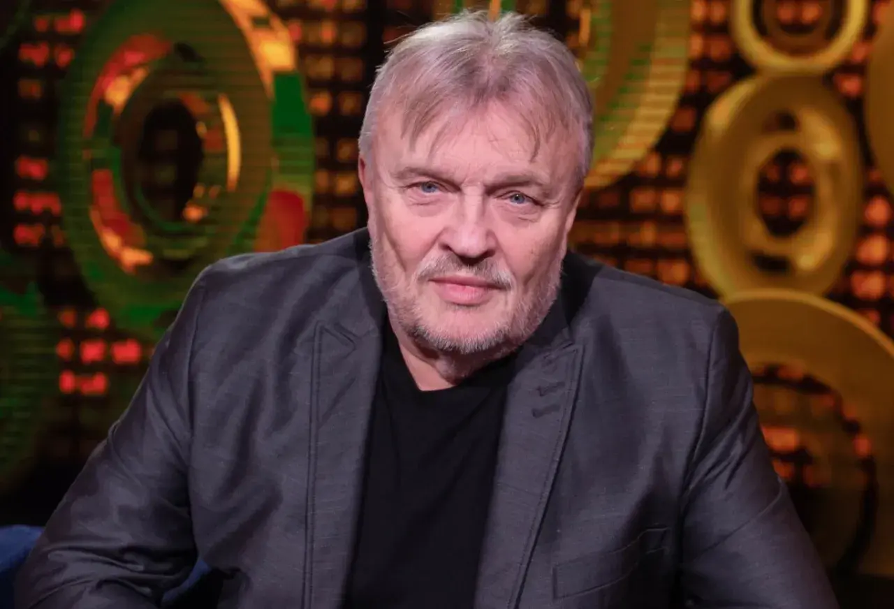 Krzysztof Cugowski, w szarym garniturze, z siwą brodą i włosami, wygląda jakby opowiadał o swoich najlepszych utworach.