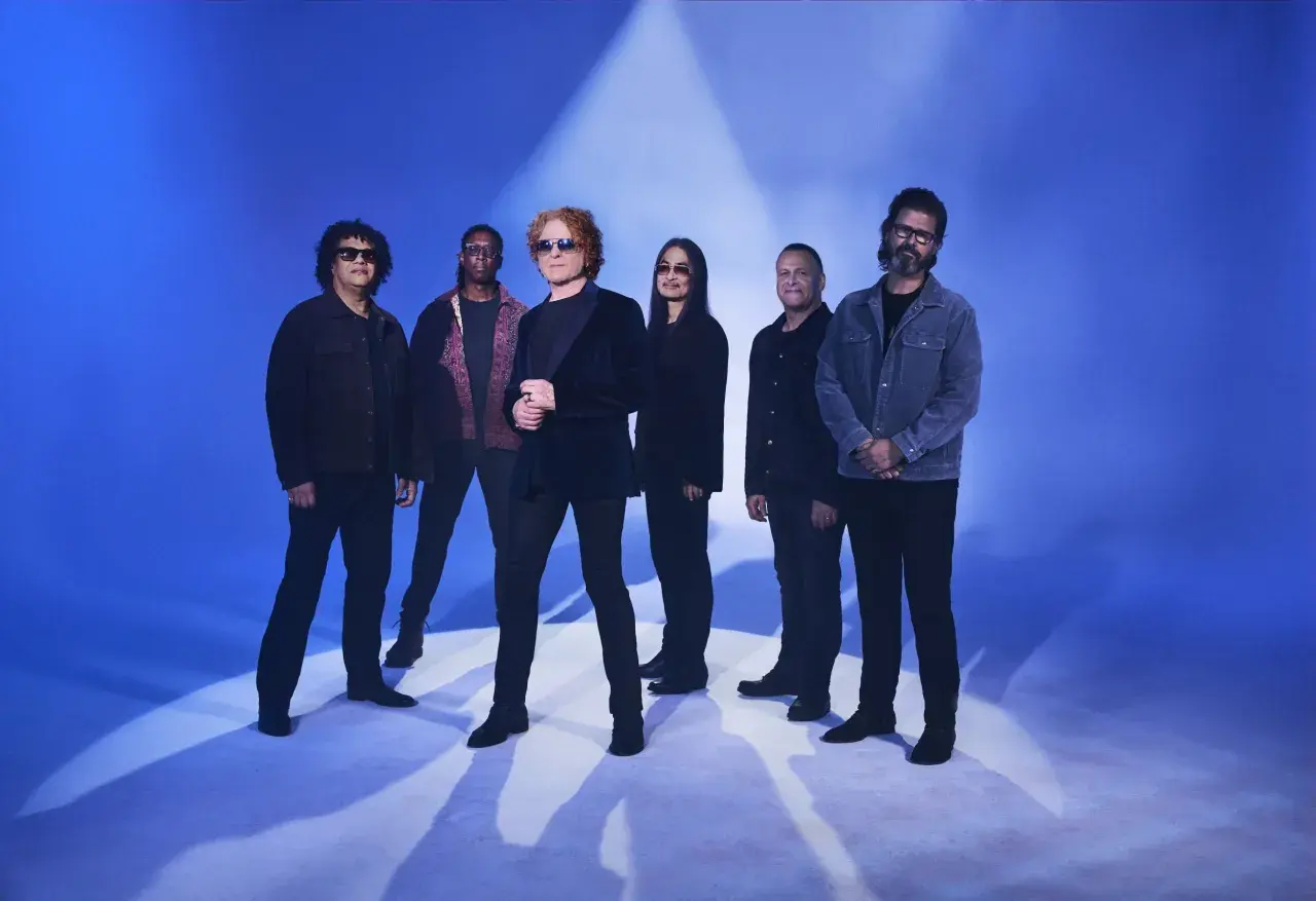 Zespół Simply Red na niebieskim tle, gotowy do koncertu.