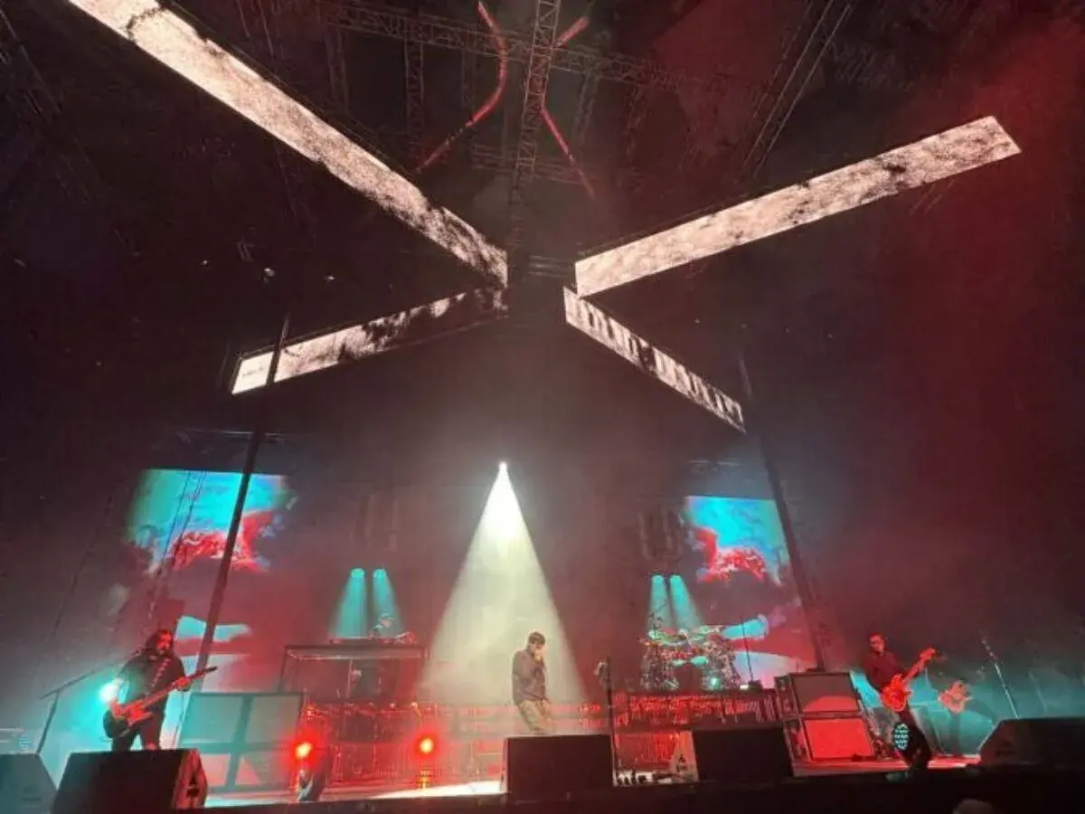Deftones koncert Polska. Wokalista na scenie, gitarzyści grają, a za nimi ekrany z wizualizacjami.