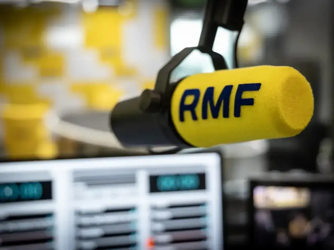 Mikrofon RMF z żółtym wiatrochronem w studiu radiowym. Słuchaj ulubionych stacje radiowe częstotliwości.