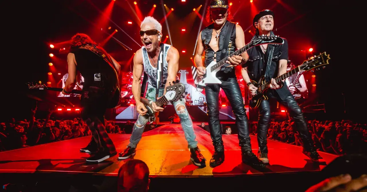 Scorpions na żywo, grając swoje legendarne utwory. Energetyczny koncert z czerwonymi światłami i tłumem fanów.