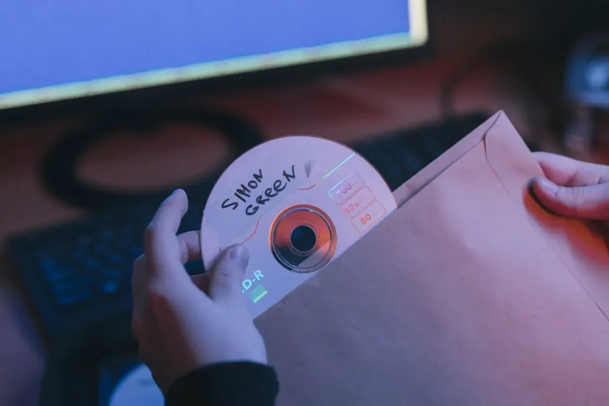 Ręce wsuwają płytę CD z napisem "Simon Green" do brązowej koperty. Może to być bootleg muzyczny.