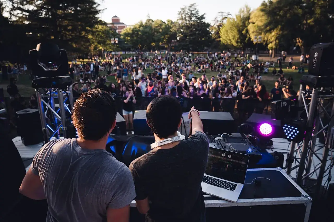 DJ-e tworzą atmosferę deep house na koncercie plenerowym. Tłum bawi się przy muzyce.