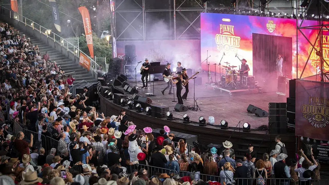 Na scenie podczas Piknik Country Mrągowo gra zespół, a publiczność w kapeluszach bawi się w rytm muzyki.
