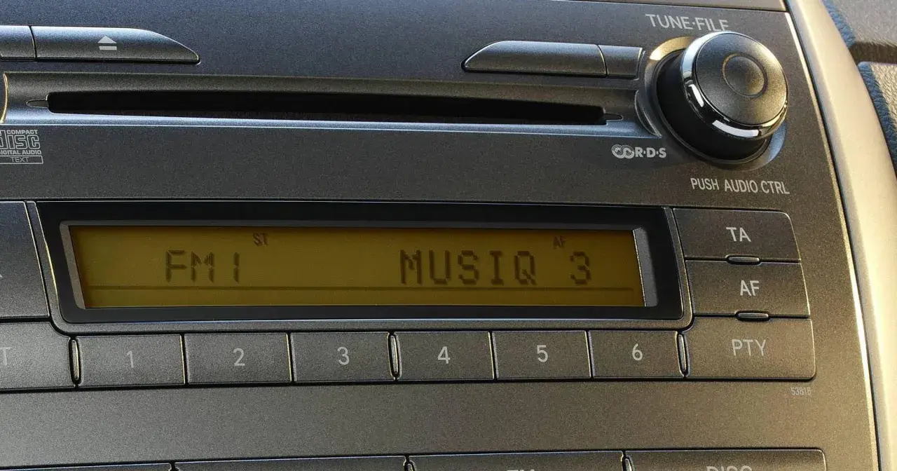 Radio samochodowe z wyświetlaczem RDS, pokazującym "FM 1 MUSIQ 3". Przyciski numeryczne i sterowanie.
