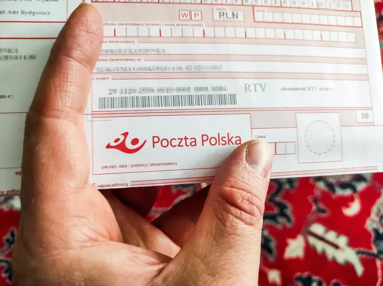 Dłoń trzyma druk Poczty Polskiej z informacją o abonamencie RTV. Kto jest zwolniony z abonamentu rtv? Sprawdź na dokumencie.