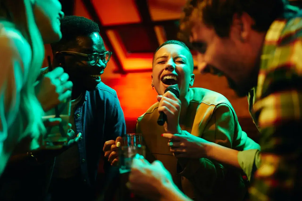 Grupa przyjaciół śpiewa na karaoke, wybierając najlepsze karaoke songs. Radość i dobra zabawa w klubie.