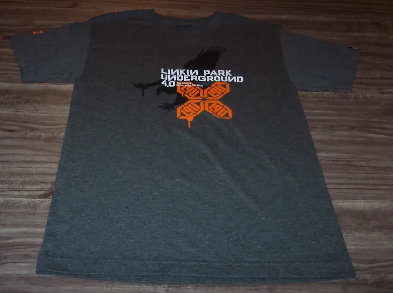 Szara koszulka z nadrukiem Linkin Park Underground 4.0, z sylwetką ptaka i pomarańczowym logo.
