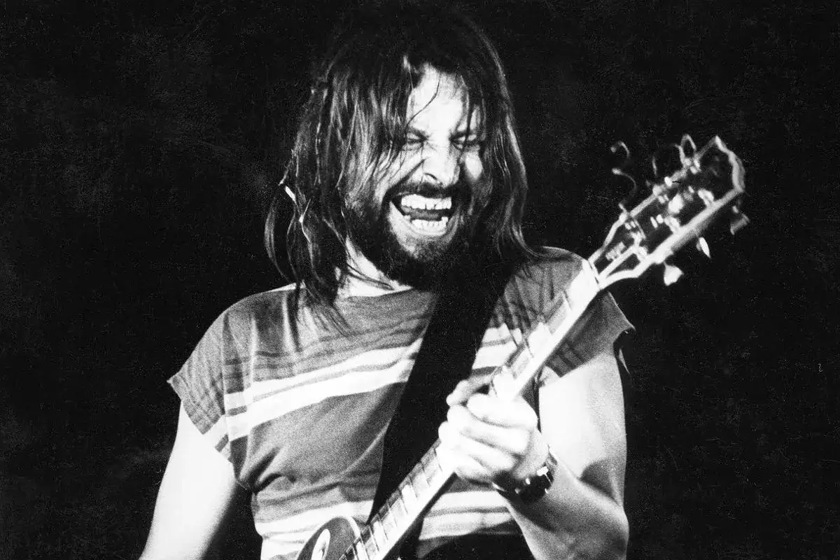 Mężczyzna z brodą i długimi włosami gra na gitarze, krzycząc z pasją. To jak tekst piosenki, kiedy byłem małym chłopcem, pełen energii.