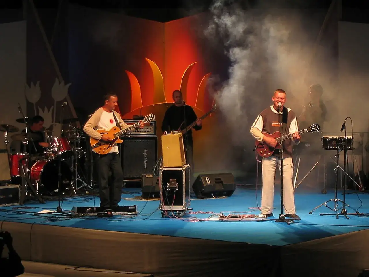 Zespół gra na scenie. Wokalista śpiewa, gitarzyści grają. Raz, dwa, trzy utwory i publiczność szaleje.