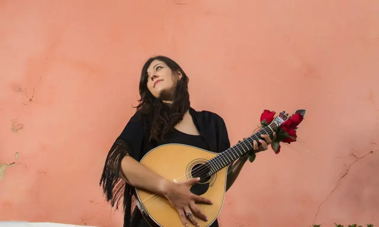 Kobieta z gitarą, ozdobioną czerwonymi różami, gotowa do wykonania wzruszającego fado.
